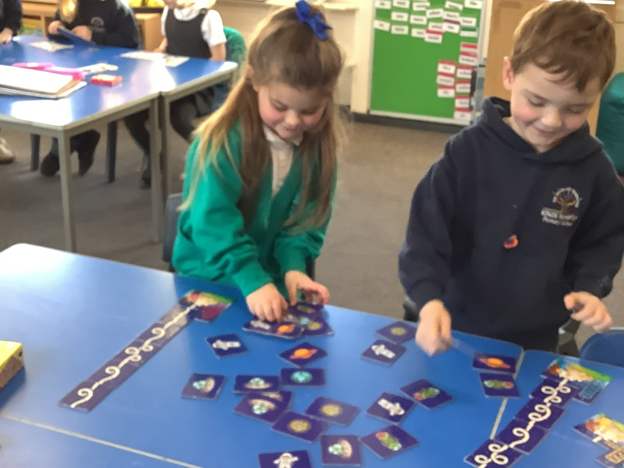 Two children using scissors to cut out words to make into sentences